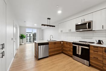 A modern kitchen with wooden cabinets and stainless steel appliances. at Ion Town Center, Shoreline, WA